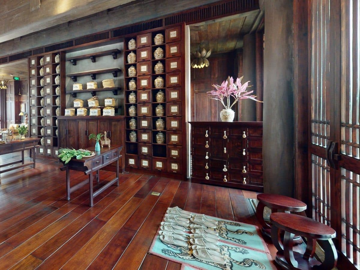 A wall of herb jars and carved wooden cabinets in the hall of Am Tuệ Tĩnh Health Care Centre.