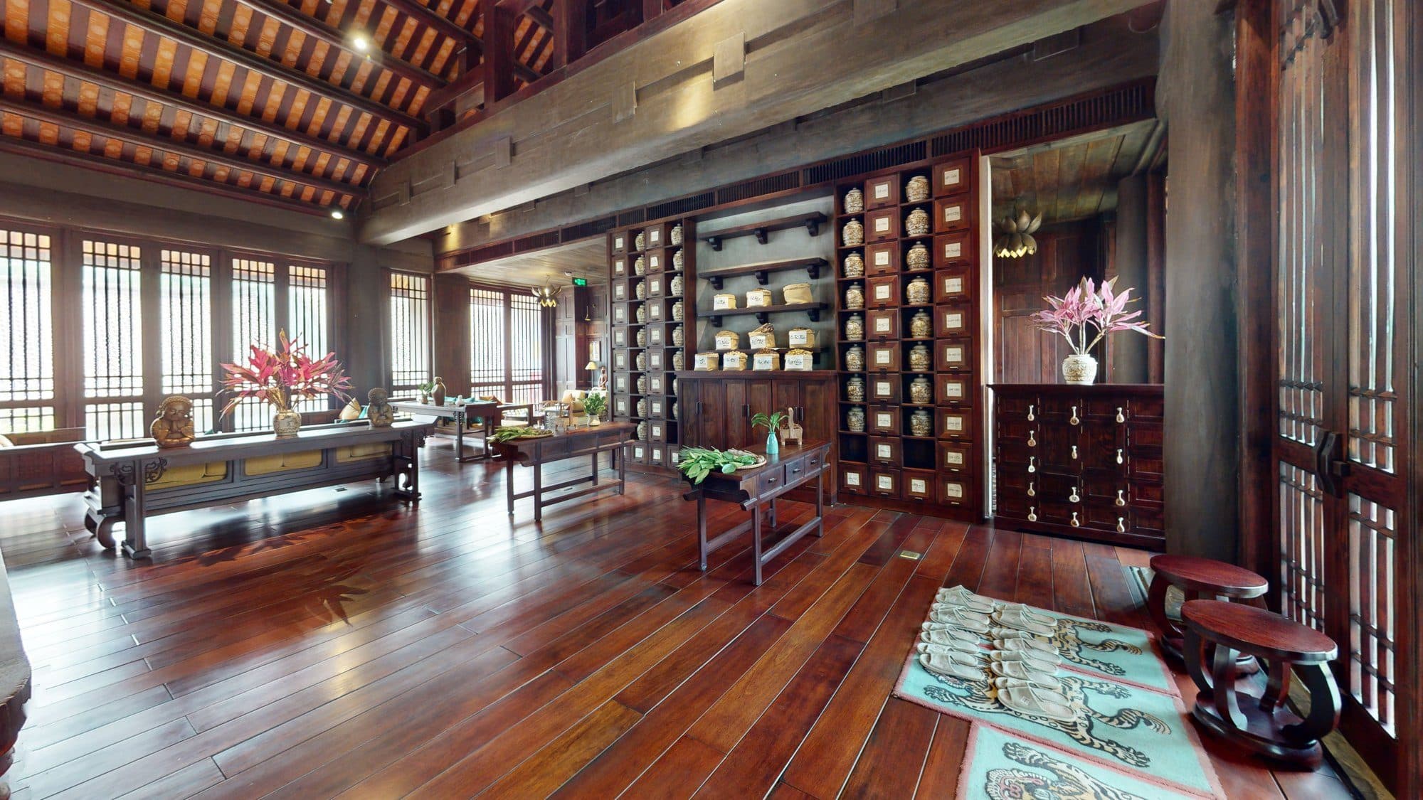 The wooden hall of Am Tuệ Tĩnh Health Care Centre, with carved beams, lattice windows and a wall of herb jars.